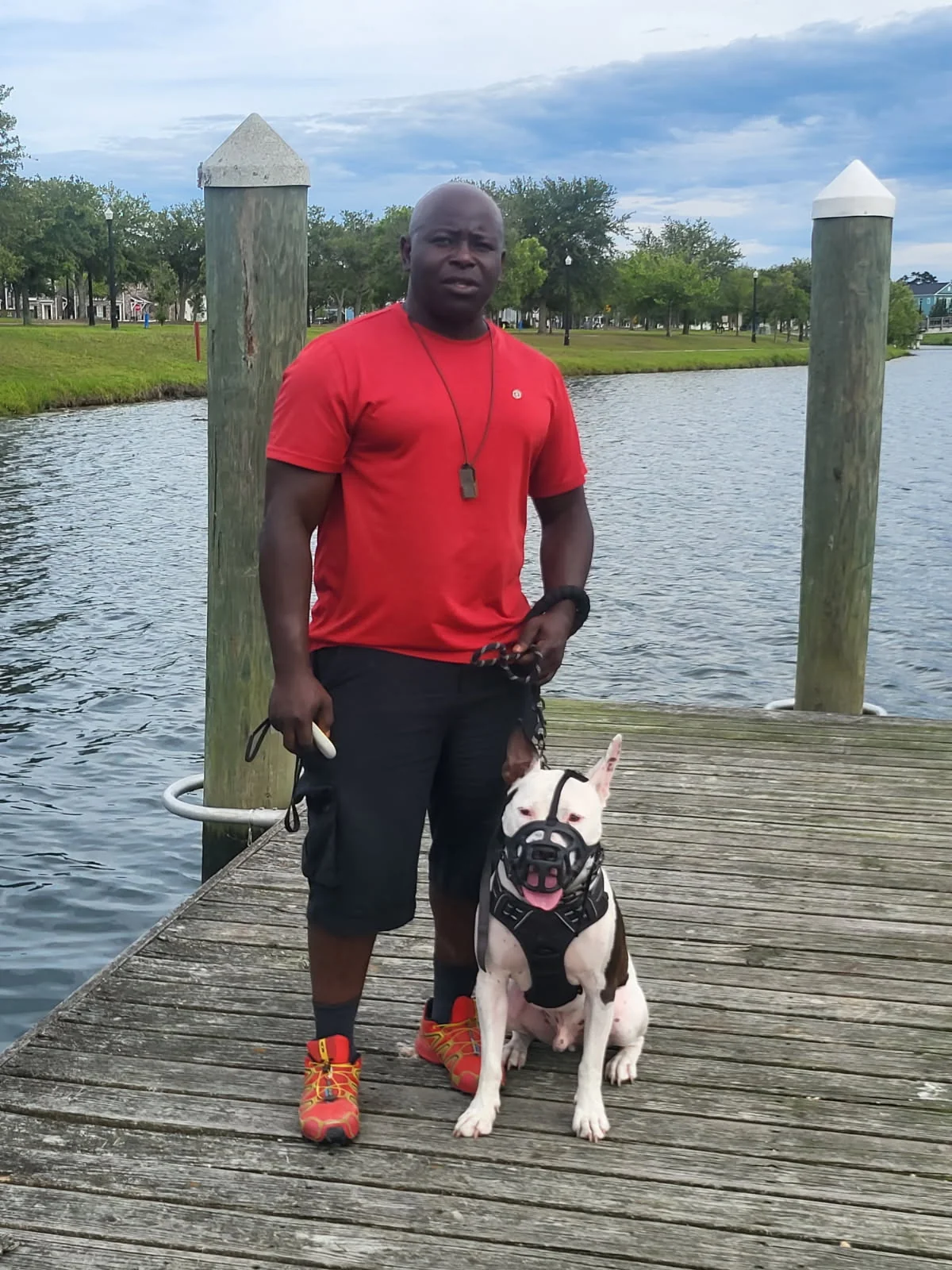 Don White with a dog calmly sitting beside him on a dock